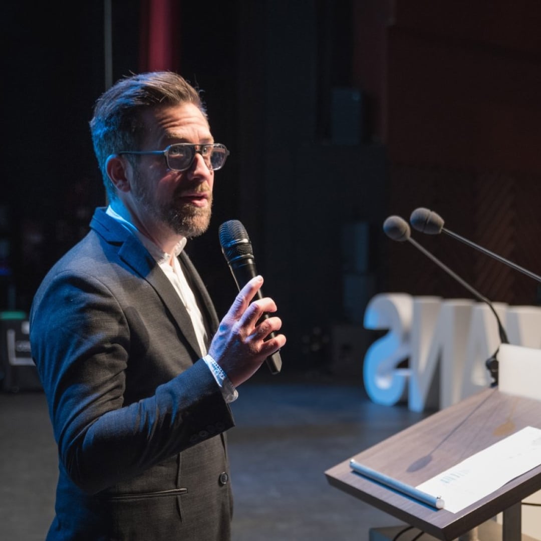 Jean-Christophe Camus sur scène, micro en main, face à une salle